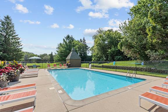A large swimming pool surrounded by lounge chairs and trees.