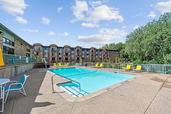 A swimming pool surrounded by chairs and buildings.