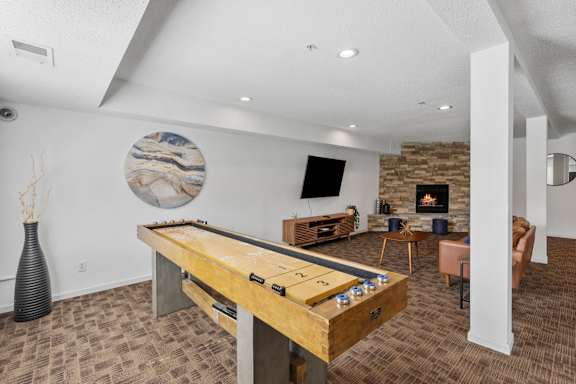 A pool table is in the middle of a room with a fireplace and a TV.