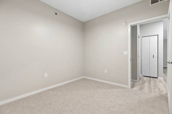 A room with a white door and carpeted floor.