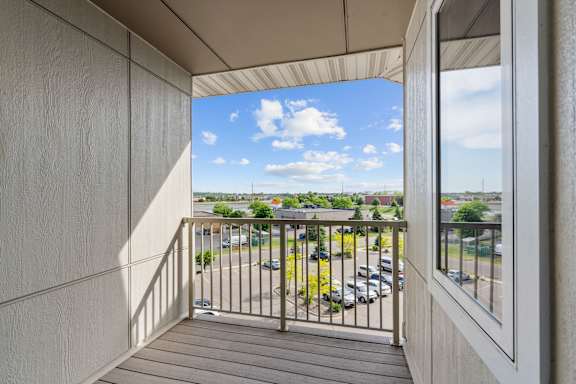 A balcony with a view of a parking lot and buildings.
