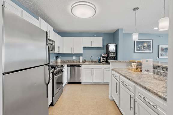 A kitchen with a refrigerator on the left and a sink in the middle.