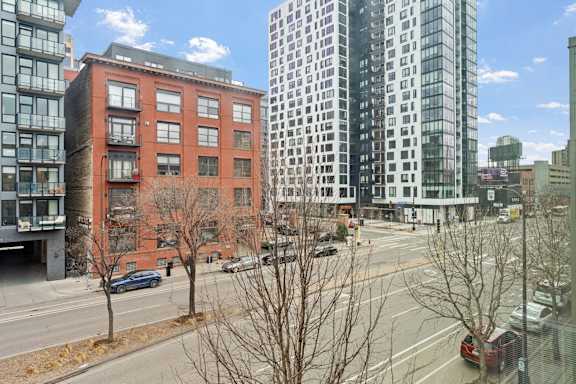 A view of a city street with a red brick building on the left and a modern glass building on the right.