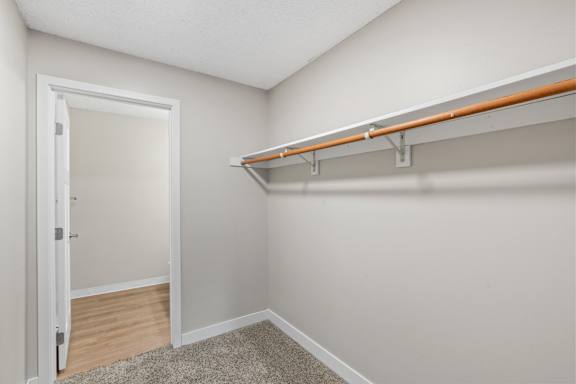 A white door is open to a room with a carpeted floor and a wall-mounted shelf with orange trim.