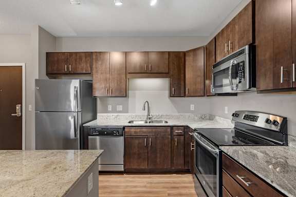 A kitchen with a granite counter top and stainless steel appliances.