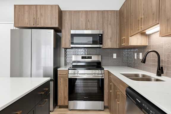 A modern kitchen with a stainless steel refrigerator, microwave, oven, and sink.