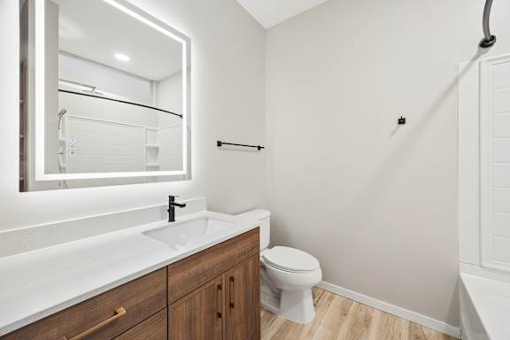 A white bathroom with a toilet, sink, and mirror.