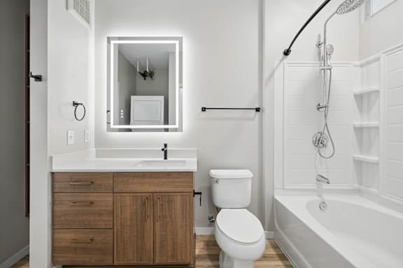 A white bathroom with a wooden cabinet and a white toilet.