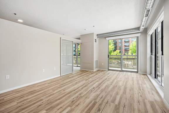 A room with wooden flooring and a sliding glass door leading to a balcony.