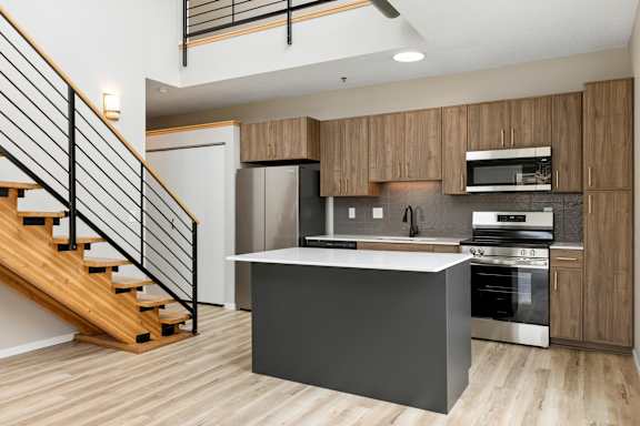 A modern kitchen with wooden cabinets and a staircase.