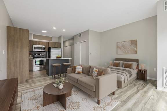 A modern living room with a kitchen area in the background.