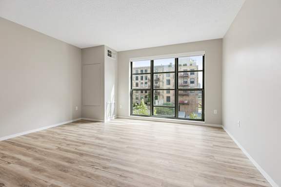 A room with wooden flooring and a large window overlooking a cityscape.