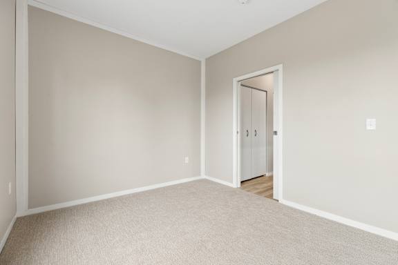 A room with a white door and carpeted floor.