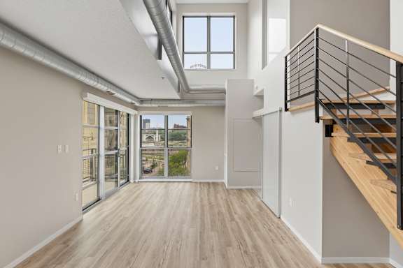 A room with a wooden floor and a staircase with a metal railing.