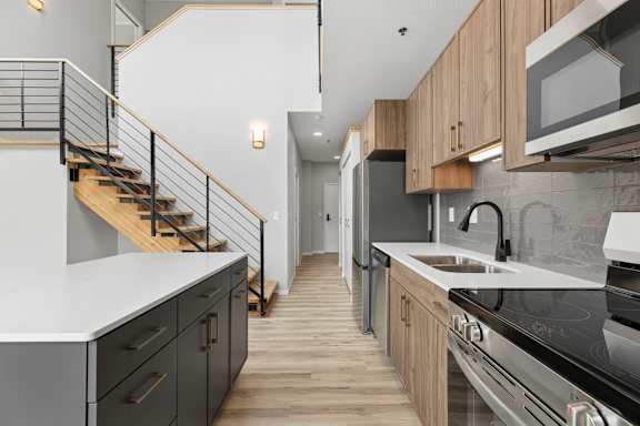 A modern kitchen with a staircase leading to the upper floor.