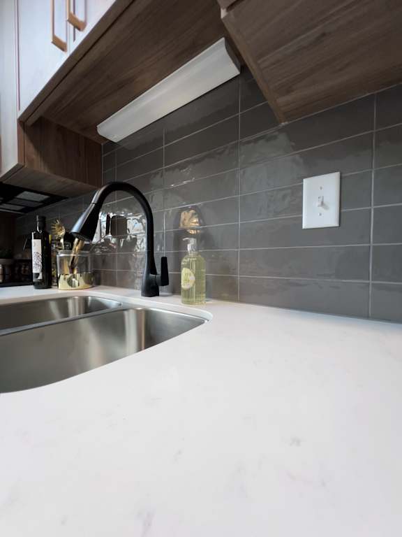 A kitchen with a white countertop and a silver sink.