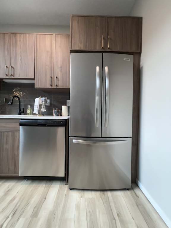 A modern kitchen with a stainless steel dishwasher and wooden cabinets.