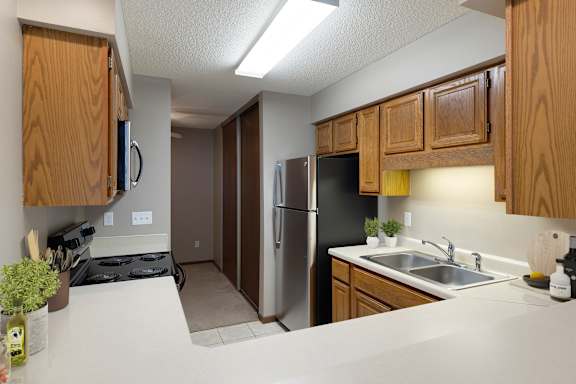 A kitchen with a refrigerator, sink, and cabinets.