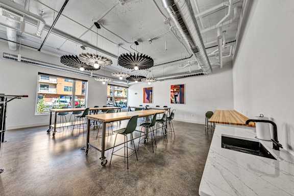 A room with a long table and chairs, a white counter, and a window with a view of a cityscape. at The Mera, St Louis Park, 55426
