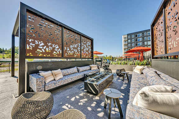 A modern outdoor seating area with a large sofa and wicker tables. at The Mera, St Louis Park, Minnesota