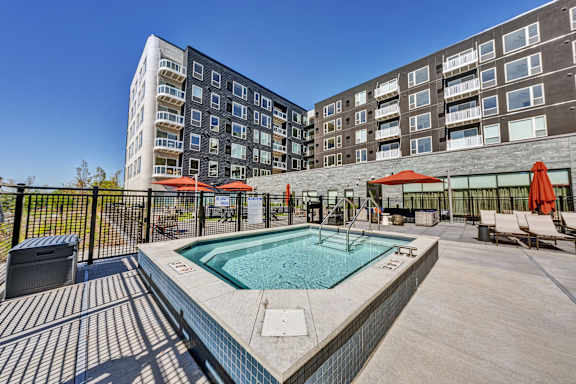 An outdoor spa surrounded by a fence and chairs. at The Mera, St Louis Park, 55426