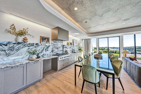 A modern kitchen with a marble countertop and a dining table set for six. at The Mera, Minnesota