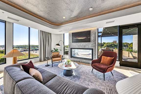 A modern living room with a grey sofa, a red chair, and a fireplace. at The Mera, Minnesota, 55426