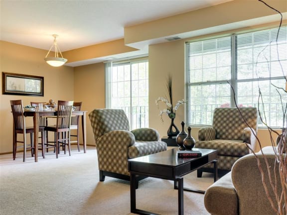 Ridge floor plan - A living room with a brown sofa, a green armchair, and a wooden coffee table at Mallard Ridge, Maple Grove, MN