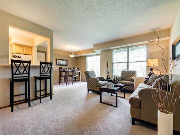 A living room with a couch, chairs, and a dining table at Mallard Ridge, Maple Grove