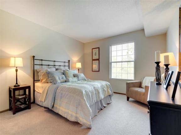 Ridge floor plan - A bedroom with a bed, chair, and two lamps at Mallard Ridge, Maple Grove, MN