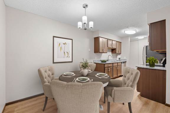 A dining room with a table set for two and a kitchen area in the background.