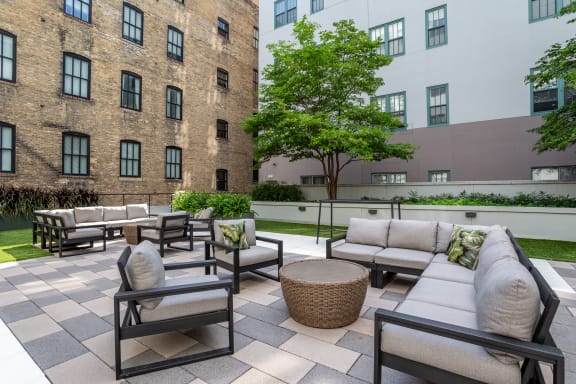 an outdoor patio area with couches and tables and a brick building