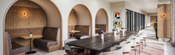 a long communal table and chairs in a room with arched doors at The Mera, St Louis Park, 55426