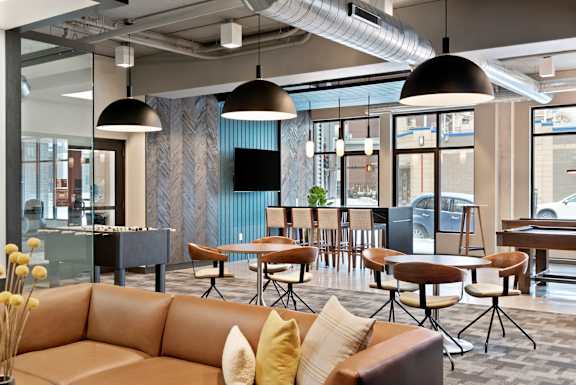 Modern office lounge with brown leather sofas and wooden tables at The Palmer, Minneapolis, 55401