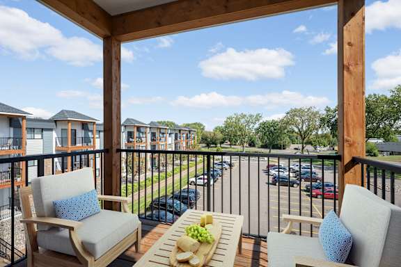 A balcony with chairs and a table with a bowl of fruit on it.