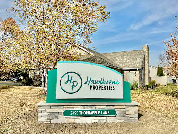 A sign for Hawthorne Properties stands in front of a house.