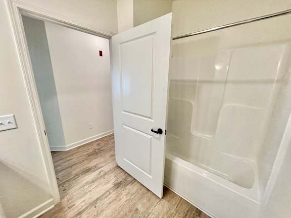 A white door is open to a bathroom with a glass shower stall.at Concord Crossing, Indiana, 47909