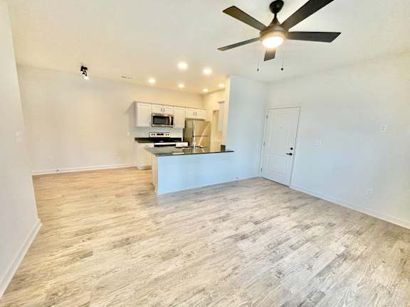 A spacious room with a ceiling fan and a kitchenette in the background.at Concord Crossing, Lafayette, 47909