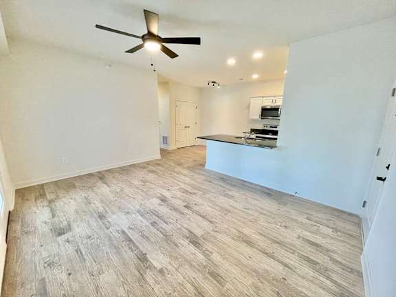 A spacious room with a ceiling fan and wooden flooring.47909