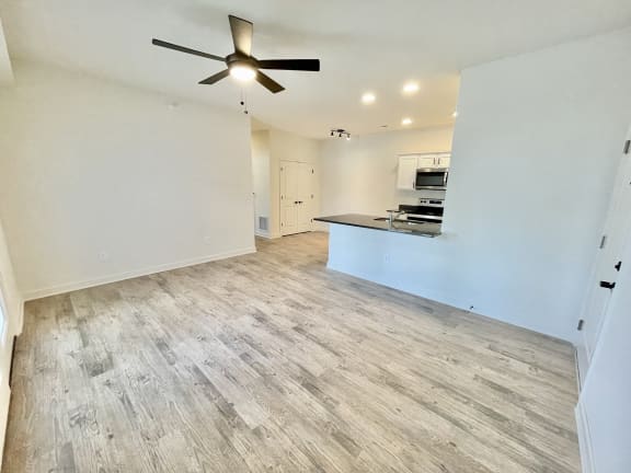 an empty living room with a ceiling fan and a kitchen in the background at Murdock Gardens Apartments, Lafayette, IN 47904