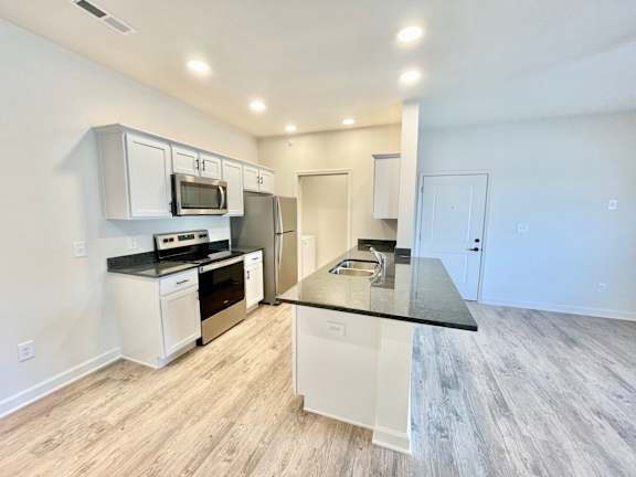 A kitchen with white cabinets and a black countertop.at Concord Crossing, Indiana