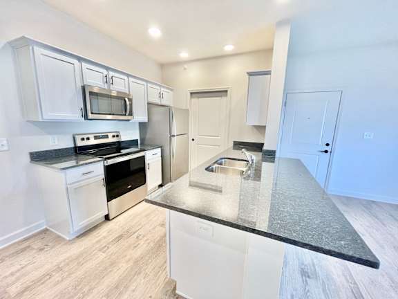 A kitchen with white cabinets and a black countertop.at Concord Crossing, Lafayette, IN