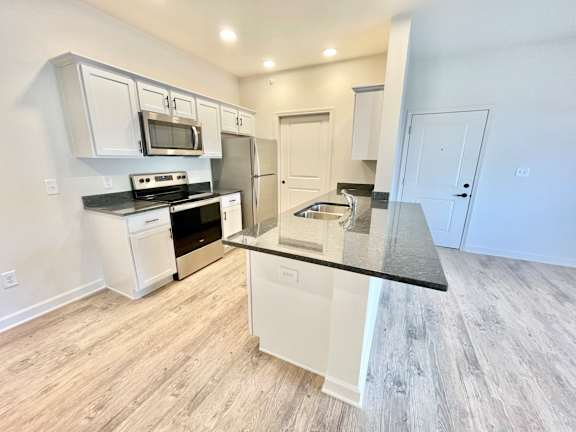 A kitchen with white cabinets and a black countertop.at Concord Crossing, Lafayette Indiana