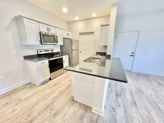 a kitchen with white cabinets and a black counter top at Murdock Gardens Apartments, Lafayette, IN 47904