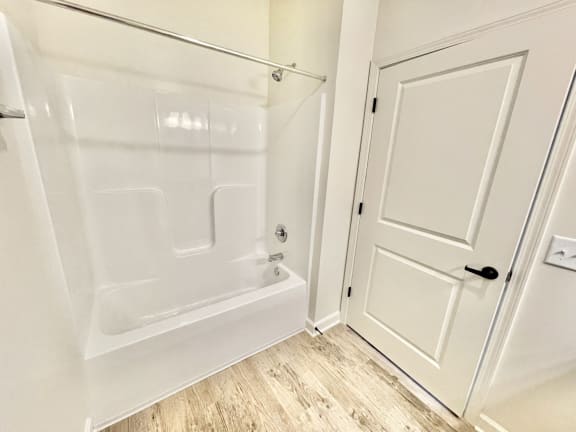 a bathroom with a bathtub and a door at Murdock Gardens Apartments, Lafayette, IN 47904