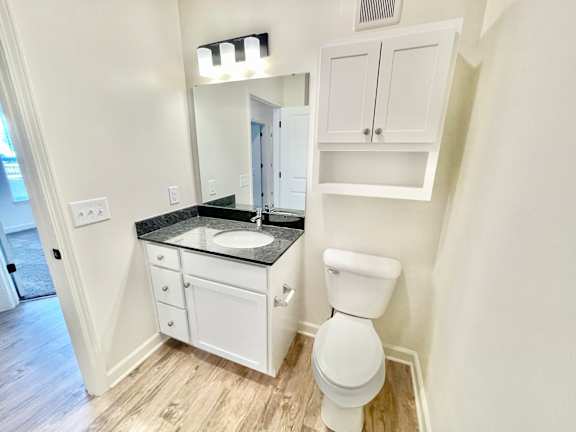 A white toilet sits in a bathroom with a sink and medicine cabinet.at Concord Crossing, Indiana