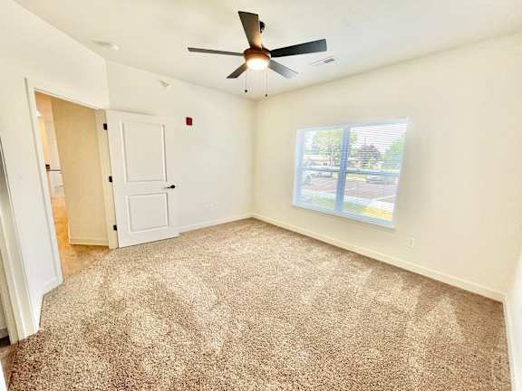 A room with a ceiling fan and a window overlooking a parking lot.at Concord Crossing, Lafayette