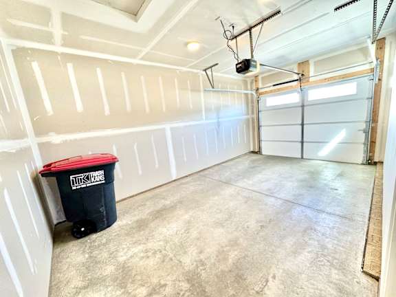 A room with a white ceiling and walls, a black trash bin, and a garage door opener.at Concord Crossing, Lafayette, 47909