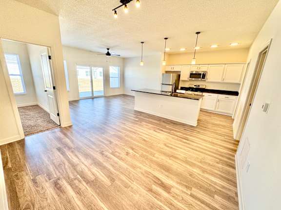 A spacious kitchen and living room with wooden flooring and white walls.at Concord Crossing, Lafayette, IN