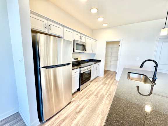 A kitchen with a stainless steel refrigerator and wooden flooring.at Concord Crossing, Indiana, 47909